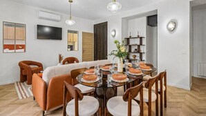 A dining area with a round table, chairs, and a central vase with flowers. - Lavie Maison - Spa Bath & AC, Heart of Saint-Merri (Paris)
