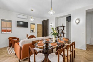 A dining area with a round table, chairs, and a central vase with flowers. - Lavie Maison - Spa Bath & AC, Heart of Saint-Merri (Paris)