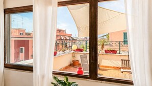 A balcony with a view of neighboring buildings, a chair, a table, and a potted plant. - Jo's Terrace - Centocelle (Roma)