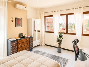 A bedroom with a bed, a dresser, a mirror, a potted plant, and a window with curtains. - Jo's Terrace - Centocelle (Roma)
