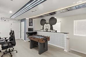 A room with a foosball table, a desk with a computer, and a large wall mural of Mickey Mouse. - 5 Bd / 4.5 Ba / Sleeps 14 / Windsor Cay Resort (Clermont)