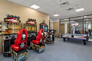 Quarto com jogos de fliperama, mesa de bilhar e janela com vista.