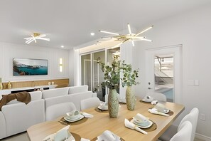 Un comedor moderno con una mesa de madera, sillas blancas y dos jarrones grandes.