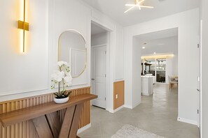 A modern interior with a wooden console table, a mirror, and a potted plant. - 5 Bd / 4.5 Ba / Sleeps 14 / Windsor Cay Resort (Clermont)