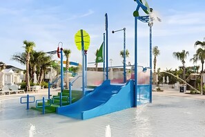 Um parque aquático com um escorregador azul e vários jatos de água.
