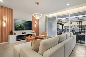 Ein modernes Wohnzimmer mit Flachbildfernseher, Kamin, einer Couch und einem Essbereich mit Aussicht.