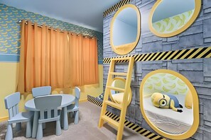 Ein Kinderzimmer mit einem runden Spiegel, einer Himmelsleiter und einem Minion-Plüschtier auf einem Bett.