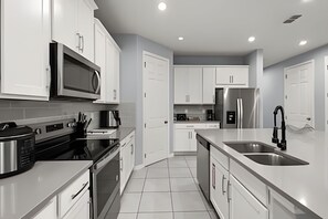 A modern kitchen with white cabinetry, stainless steel appliances, and a central island with a sink. - 7 Bd / 6,5 Ba / Sleeps 18 / Solara Resort (Kissimmee)