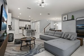 A modern living room with a grey sectional sofa, a round coffee table, and a TV on the left. - 7 Bd / 6,5 Ba / Sleeps 18 / Solara Resort (Kissimmee)