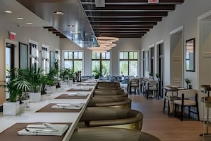 A spacious, modern dining area with long tables and chairs, large windows, and a high ceiling with exposed beams. - 7 Bd / 6,5 Ba / Sleeps 18 / Solara Resort (Kissimmee)