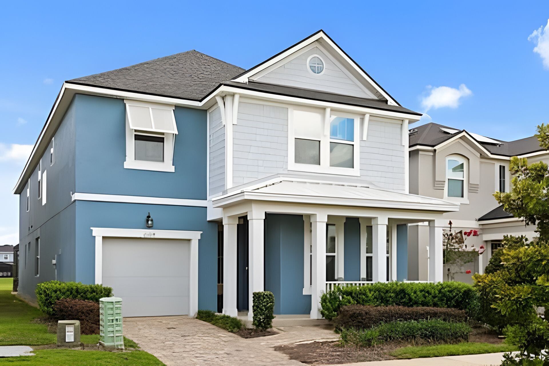 A two-story residential house with a front porch, garage, and a well-maintained lawn.