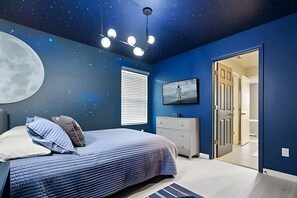 A bedroom with a bed, a dresser, a nightstand, a painting, and a door leading to another room. - 7 Bd / 6,5 Ba / Sleeps 18 / Solara Resort (Kissimmee)
