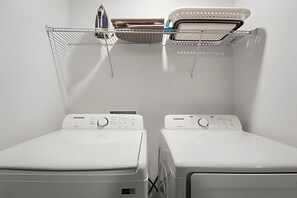 Two white front-loading washing machines with control panels, a drying rack above them, and a white wall in the background. - 3 Bd / 3 Ba / Sleeps 8 / The hub (Kissimmee)