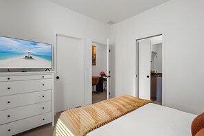 A bedroom with a bed, a dresser, a television, and a door leading to a bathroom. - 3 Bd / 3 Ba / Sleeps 8 / The hub (Kissimmee)