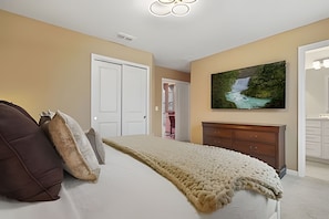 A bedroom with a bed, a painting, a dresser, and a door. - 8 Bd / 6 Ba / Sleeps 23 / Windsor Cay Resort (Clermont)