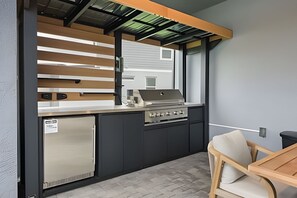 A compact kitchen with a built-in refrigerator, a gas stove, and a window overlooking a residential area.