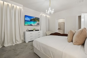 Een slaapkamer met een groot bed, een tv aan de muur, een dressoir en een spiegel.
