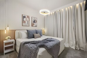 A modern bedroom with a large bed, bedside lamps, a nightstand, and abstract wall art. - 8 Bd / 6 Ba / Sleeps 23 / Windsor Cay Resort (Clermont)