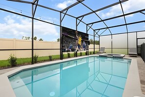 A swimming pool with a clear blue water surface, surrounded by a glass enclosure with a metal frame.
