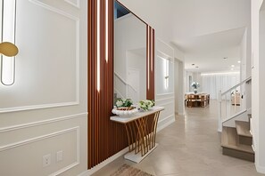 A modern interior with a staircase, a dining area, and a hallway with a decorative console. - 8 Bd / 6 Ba / Sleeps 23 / Windsor Cay Resort (Clermont)