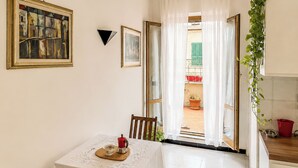A dining area with a table set for two, a painting on the wall, and a view of the outside through an open door. - Terrazza di Jo (Roma)