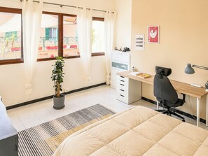 A bedroom with a bed, a desk, a chair, a potted plant, and a window with curtains. - Terrazza di Jo (Roma)
