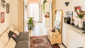 A modern living room with a sofa, a coffee table, a rug, a mirror, and a kitchen area in the background. - Terrazza di Jo (Roma)