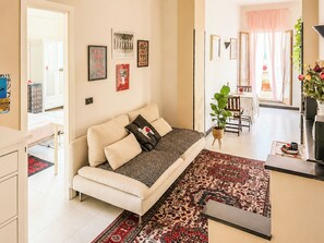 A modern living room with a sofa, a dining area, and a kitchen visible in the background. - Terrazza di Jo (Roma)