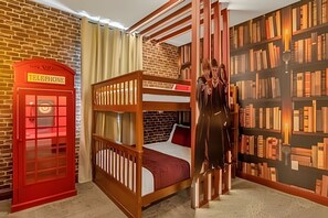 Een kamer met een stapelbed, een rode telefooncel en een boekenkast.