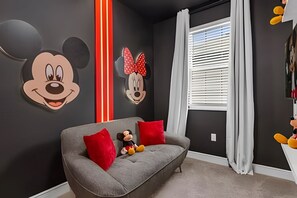 A room with a grey sofa, red cushions, and two Mickey Mouse cutouts on the wall. - 6 Bd / 3,5 Ba / Sleeps 22 / Reunion Village (Kissimmee)