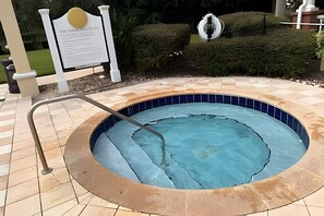 A circular swimming pool with a tiled edge, a metal ladder, and a sign with text in the background. - 6 Bd / 3,5 Ba / Sleeps 22 / Reunion Village (Kissimmee)