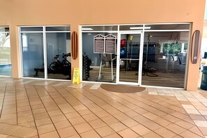 A building entrance with glass doors, a yellow caution sign, and a bicycle parked inside. - 6 Bd / 3,5 Ba / Sleeps 22 / Reunion Village (Kissimmee)