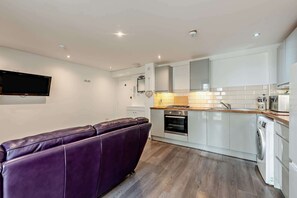 A modern kitchen with white cabinets, a built-in oven, and a washing machine. - Host & Stay | Clarendon Violet (Brighton and Hove)
