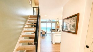 Een trap naar een kamer met uitzicht op zee, een eetgedeelte en een keuken.