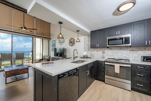 A modern kitchen with dark cabinets, stainless steel appliances, and a large island. - Napili Point | Water Front | 3 Free Cars | KBM Resorts  | 3 Multi-Unit Listings, 6 Bedrooms | NAP ML-4077 (Lahaina)