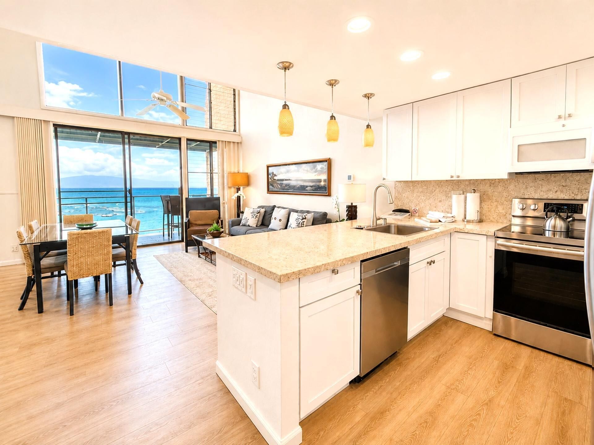 A modern kitchen with a central island, stainless steel appliances, and a view to the ocean.