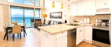 A modern kitchen with a central island, stainless steel appliances, and a view to the ocean.