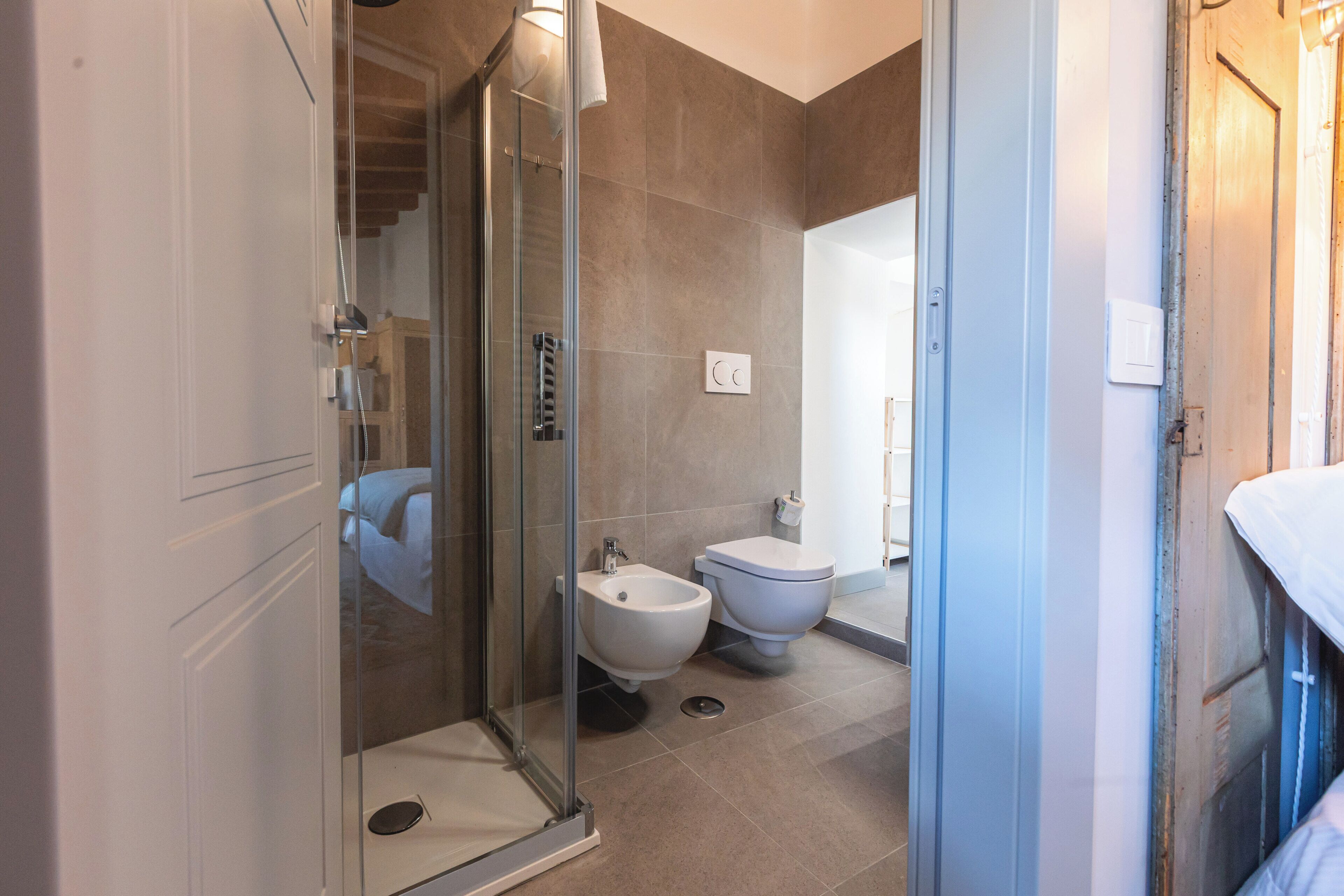 Ein modernes Badezimmer mit Duschkabine aus Glas, einem Bidet und einer Toilette.