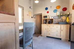 A kitchen with a wooden cabinet, a chair, and a tiled backsplash. - Palazzo San Biagio – In the heart of Viterbo’s historic center (Viterbo)