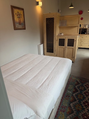 A hotel room with a bed, a wooden wardrobe, a kitchen area, and a framed picture on the wall. - Palazzo San Biagio – In the heart of Viterbo’s historic center (Viterbo)