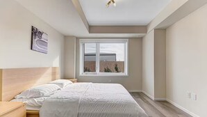A bedroom with a large bed, a nightstand, a window with a view, and a ceiling light fixture. - Family-Friendly Richmond Hill Home • Pet • Parking (Richmond Hill)