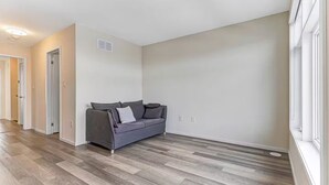 A room with a grey sofa, wooden flooring, and a window. - Family-Friendly Richmond Hill Home • Pet • Parking (Richmond Hill)