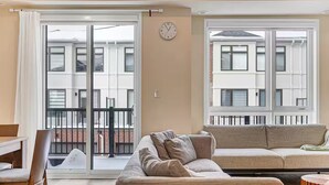 A living room with a sofa, a chair, a table, and a window with a view of a building. - Family-Friendly Richmond Hill Home • Pet • Parking (Richmond Hill)
