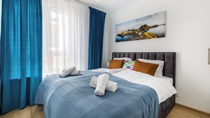 Una habitación de hotel con cama, un cuadro y una ventana con cortinas.
