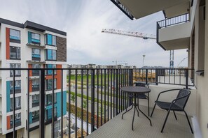 Ein Balkon mit Tisch und Stühlen, mit Blick auf eine Baustelle mit Kränen und Gebäuden.