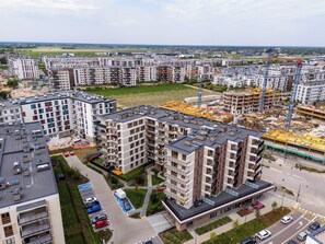 Ein Hochhaus mit mehreren Balkonen, einem Parkplatz und einer Baustelle im Hintergrund.