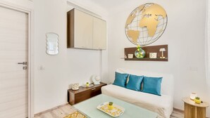 Una camera d'albergo con un letto, un comodino, un piccolo tavolo con vassoio, una sfera geografica decorativa e una mensola con oggetti ornamentali.