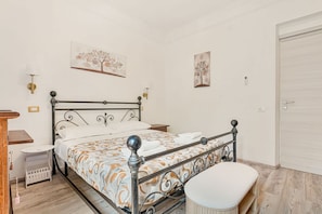 A bedroom with a metal bed frame, a bedside table, a chair, and a wall-mounted light fixture. - [LemonTree] Air conditioning-Near the station (La Spezia)