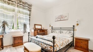 Una camera da letto con una struttura letto in metallo, comodini in legno, una panca e una finestra con tende.