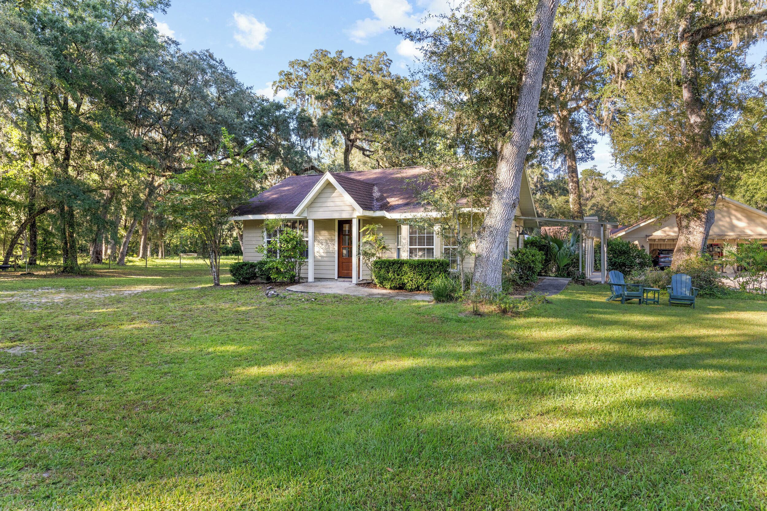 A single-story house with a front porch, surrounded by a well-maintained lawn and trees.
